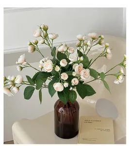 Vue détaillée de roses artificielles crème dans un vase en verre brun décoratif