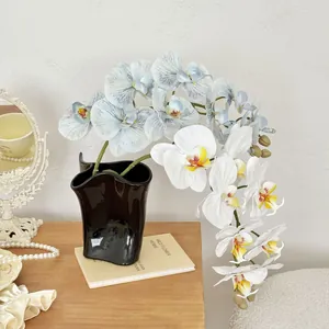 Realistic 9-head white and blue butterfly orchid in a wave-edge black ceramic vase