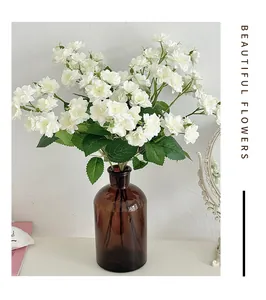 White silk roses in a brown amber glass vase on a white tabletop minimalist decor