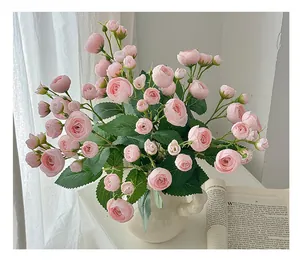 Gros plan de boutons de camélia artificiels roses dans un vase en céramique blanche