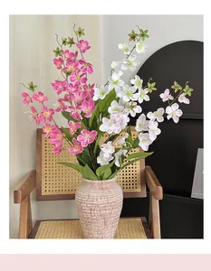 Dettaglio di fiori di gelsomino artificiali rosa in un vaso di ceramica testurizzato e foglie