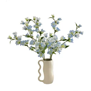 Fiori di mughetto finti blu in un vaso di ceramica ondulato per decorazione d'interni