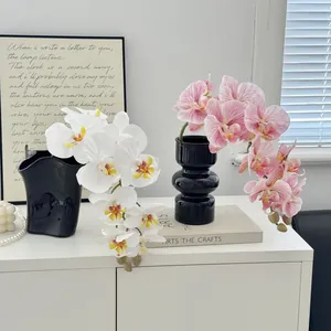 Realistic white and pink orchid arrangement in modern black ceramic vases for home decor