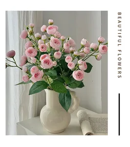 Détail d'un bouquet de camélias roses artificiels dans un vase en céramique blanc