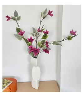 Vue détaillée de clématites 3D magenta dans un vase géométrique en céramique blanche