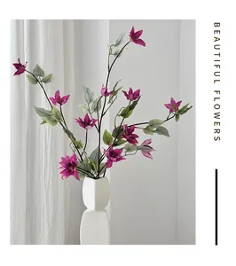 Gros plan artistique de clématites en soie violette dans un vase géométrique blanc en céramique