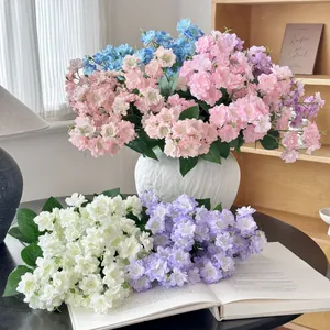 Artificial jasmine and begonia flower bouquet in a white ceramic vase on a wooden table
