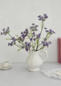 Detailed view of purple lace artificial flowers in a white ceramic vase on a desk