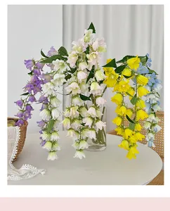Primer plano de flores artificiales de lirio de los valles colgantes en un jarrón de cristal