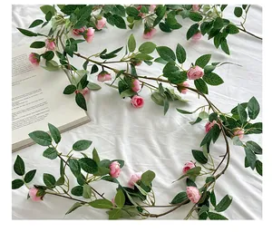 Primer plano de enredadera de rosas rosas artificiales con hojas sobre tela blanca