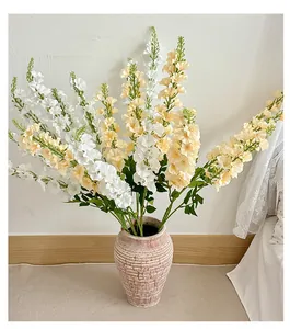 Detail of white and champagne faux larkspur flowers in a rustic ceramic vase