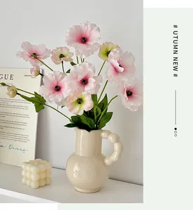 Detail of pink faux butterfly ranunculus in a creative beige ceramic vase