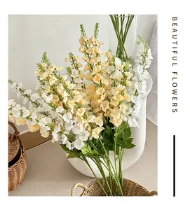 Detail of cream and white artificial larkspur flowers in a stone textured vase