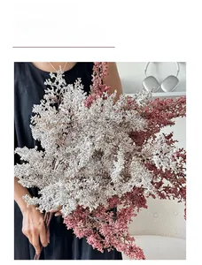 Dettaglio di un bouquet di fiori artificiali stile wabi-sabi tenuto da una persona