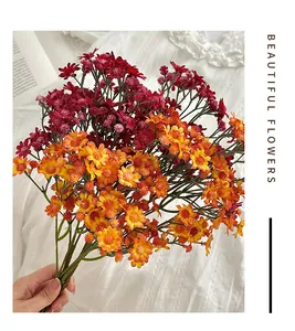 Detailweergave van een handgehouden boeket kunstmatige madeliefjes in rood en oranje