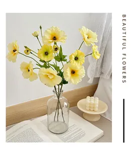 Detail of yellow artificial ranunculus petals and transparent glass vase for home decor