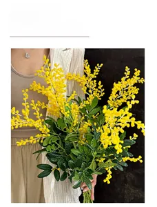 Gros plan de fleurs d'acacia jaunes artificielles avec des feuilles vertes déco