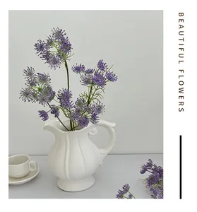 Detail of purple artificial lace flowers in a white ribbed ceramic vase with handle