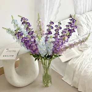 Artificial Delphinium bouquet in purple and blue hues inside a glass vase