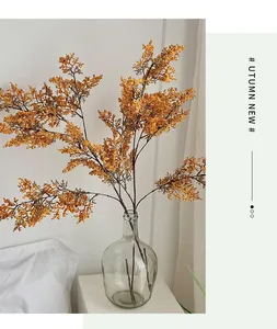 Dettaglio di rami di fiori artificiali giallo zenzero in un vaso di vetro tondo