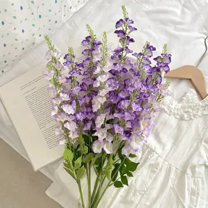 Faux purple larkspur flowers for home decor with long stems on white linen background