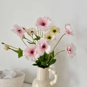 Artificial ranunculus flowers in a beige ceramic vase for home and table decoration
