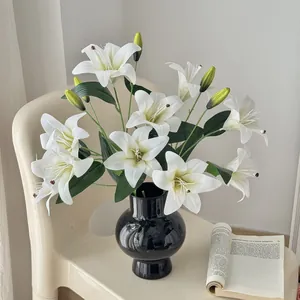 Elegant black ceramic vase with realistic white lilies set on a minimalist cream chair