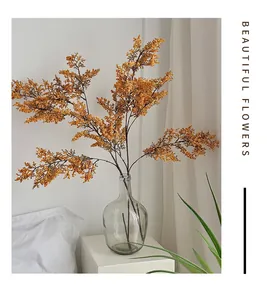 Dettaglio di fiori finti dorati in vaso di vetro per decorazione casa minimalista