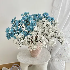 Blauw en wit kunstmatig madeliefboeket in keramische vaas op een bijzettafel