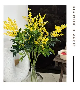 Vue détaillée de fleurs de mimosa artificielles jaunes dans un vase en verre clair