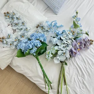 Detailed top view of faux blue hydrangea and orchid bouquet on white bedding