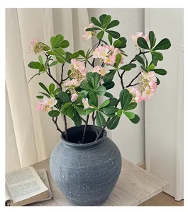 Détail de fleurs roses artificielles dans un vase en céramique bleue sur une table en bois