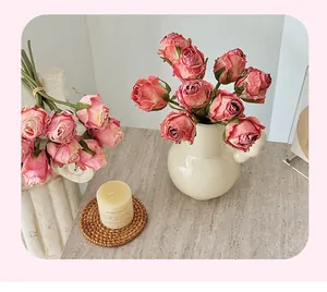 Détails d'un bouquet de roses artificielles rétro dans un vase en céramique sur marbre