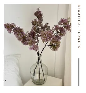 Purple faux asparagus fern stems displayed in a glass vase for home decor