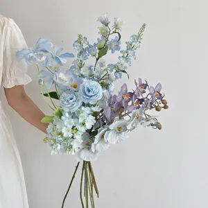 Detail of blue faux roses and purple orchids held by a model for home decoration