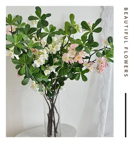 Détail de feuilles de pittosporum artificielles et fleurs rose-blanc en vase