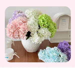 Detailed view of artificial hydrangea silk flowers in a white ceramic vase on wood surface