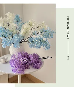 Detailed close-up of blue, white, and purple artificial lilac flowers in a white ceramic vase