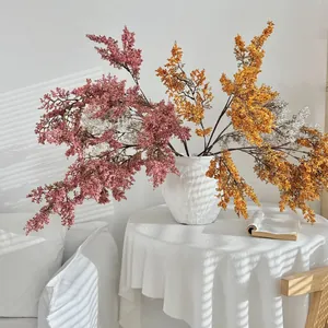 Bouquet di fiori finti in vaso di ceramica bianca con ombre di luce solare naturale