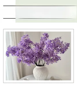 Close-up of dense purple artificial lilac flowers in a white textured ceramic vase