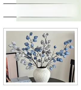 Detail view of blue and grey artificial Physalis flowers in a white ceramic rock vase