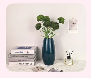 Claveles verdes artificiales en un jarrón de cerámica azul para decoración moderna