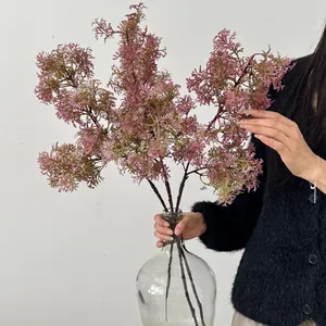Three realistic pink artificial pine branches in a glass vase for home decoration