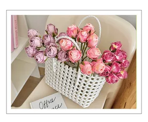 Vue détaillée de roses artificielles roses et violettes dans un panier tressé blanc