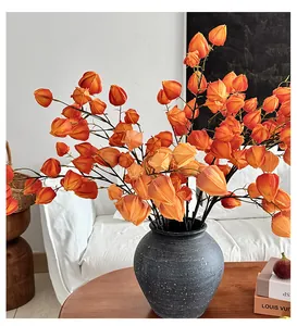 Detail of vibrant orange artificial physalis branches in a matte grey ceramic vase
