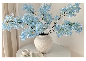 Close-up of light blue artificial lilac flowers in a white ceramic vase for home decor