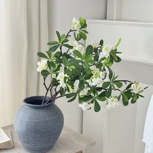 Branches de pittosporum artificiel avec fleurs blanches dans un vase en céramique grise