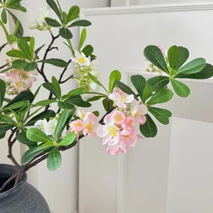 Branches de fleurs de pittosporum artificielles roses dans un vase en céramique gris