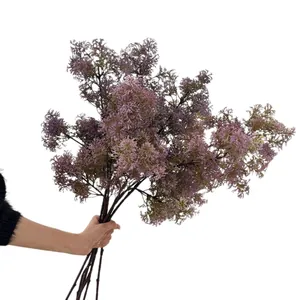Artificial purple frosted pine branches for living room decor held against white background