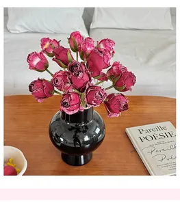 Bouquet de roses vintage en vase céramique noir sur table bois avec livre français